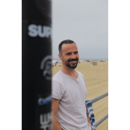 man in white shirt smiling in front of beach