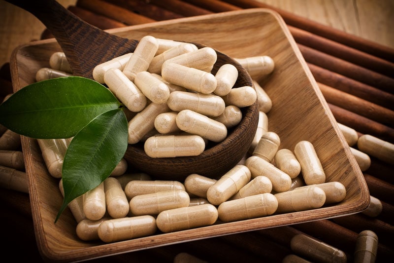 supplement capsules in wooden bowl