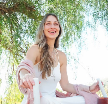 Smiling woman sitting cris-crossed under tree