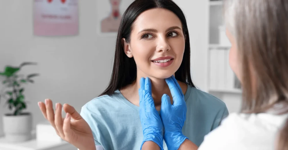 Healthcare practitioner examining a patient’s neck during a thyroid consultation.