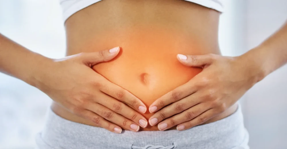 Woman holding her lower abdomen, representing digestive discomfort or gut health issues.
