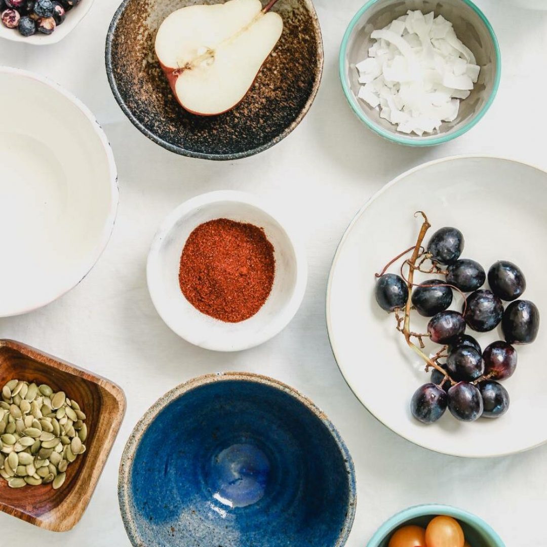 joanie-simon-2r8BzVYZIeo-unsplash (1) bowls of grapes, pear, cherry tomatoes, seeds, and other nutritious items